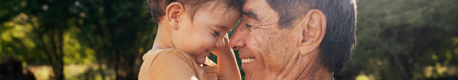 Grandfather holding grandchild outdoors.